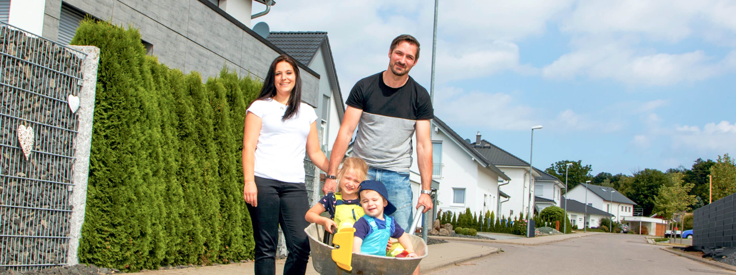 Junge Familie mit zwei Kindern in der Schubkarre