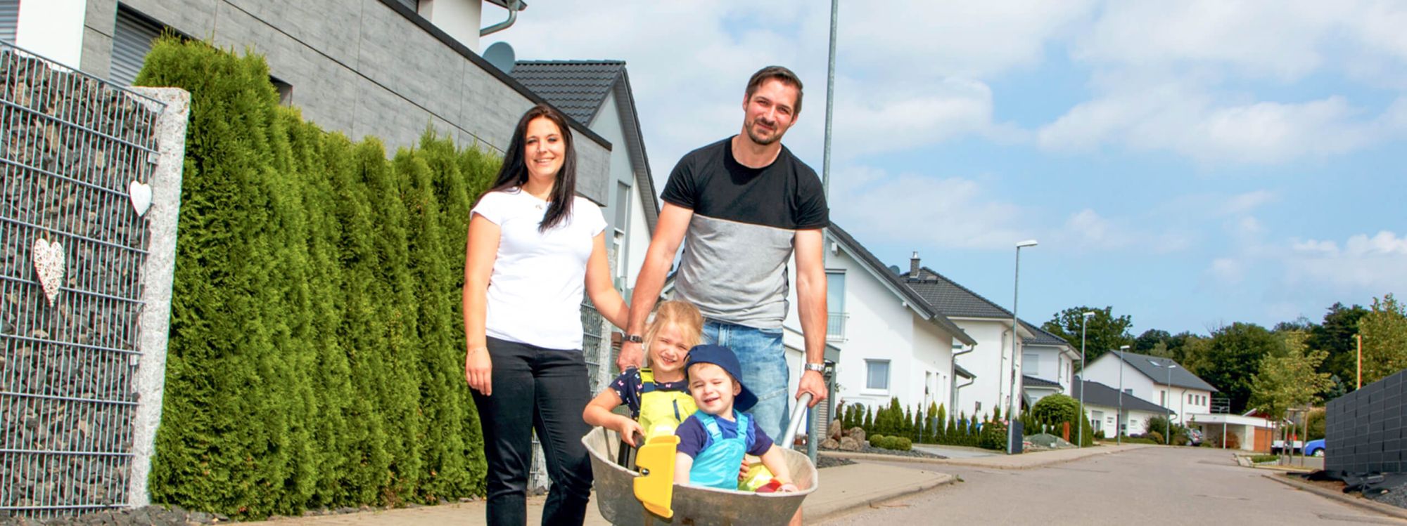 Junge Familie mit zwei Kindern in der Schubkarre